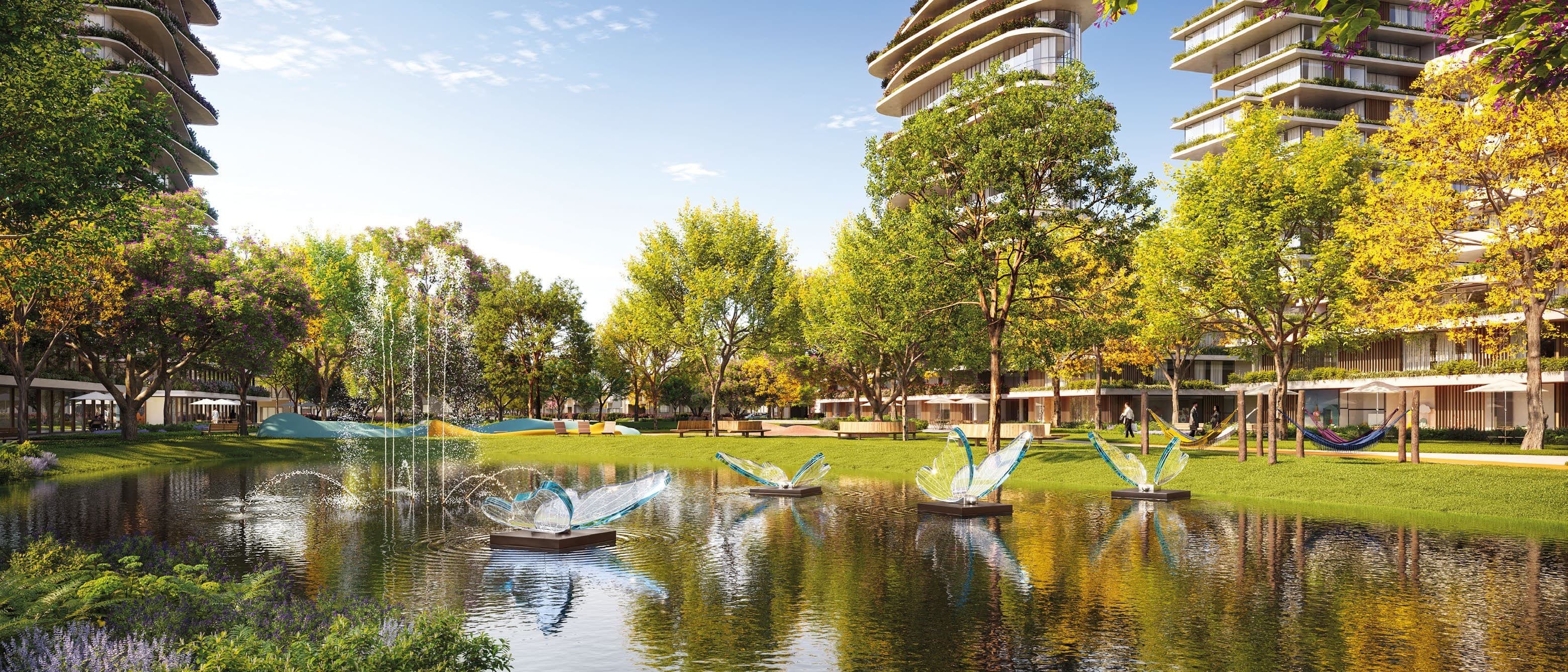 O parque do Vivapark: lago com esculturas, gramado, redes e os prédios recuados entre as árvores